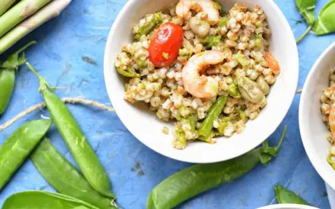 Deliziosa insalata di cereali con gamberetti, pomodorini, asparagi e fave. Un piatto fresco e nutriente.