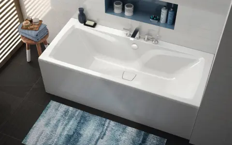 Baignoire blanche moderne, d'une largeur baignoire standard, avec robinetterie chromée et étagère murale.