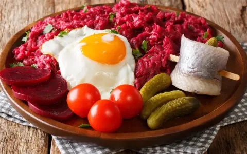 Labskaus: was ist das? Ein deftiges Gericht mit Roter Bete, Kartoffeln, Corned Beef, Spiegelei, Rollmops und Gewürzgurken.