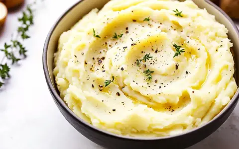 En skål med krämigt potatismos lyx, toppat med örter och peppar. Perfekt som tillbehör till middagen.