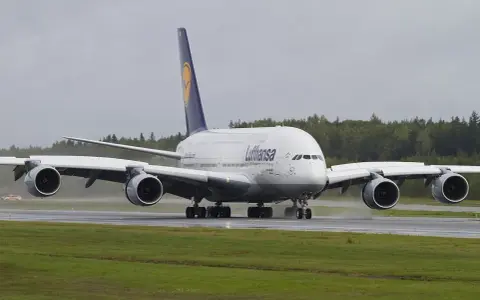 Lufthansa A380, największy samolot pasażerski, kołuje po mokrym pasie startowym.