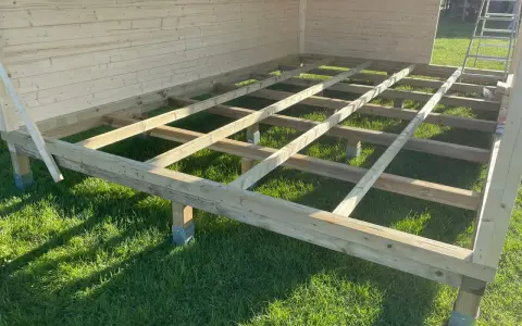 Holzkonstruktion für das Gartenhaus. Der Boden wird auf Balken und Pfosten errichtet, die auf dem Rasen stehen.