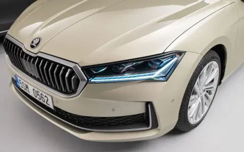 Nowy Skoda Superb 2024 w beżowym kolorze, z charakterystycznym grillem i nowoczesnymi światłami LED.
