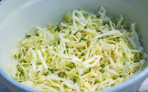 Frischer spitzkohl salat mit Schnittlauch und Chili-Flocken, appetitlich in einer Schüssel angerichtet.