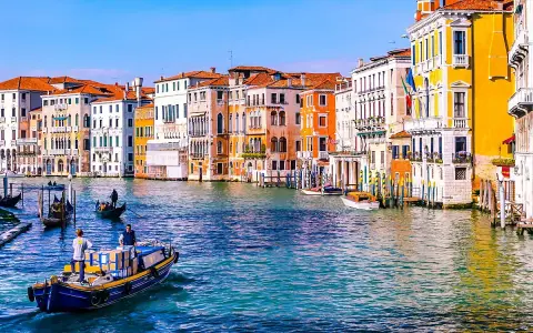 Gondole e vaporetti sul Canal Grande, un assaggio di cosa vedere a Venezia in due giorni. Palazzi colorati e acqua scintillante.