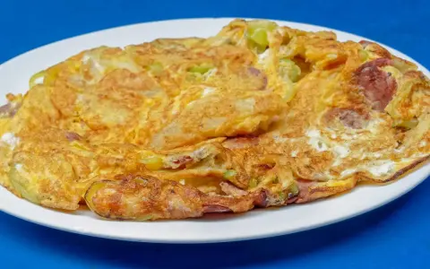Złocisty omlet z warzywami i kawałkami kiełbasy, idealny przykład, jak się robi omlet dietetyczny.