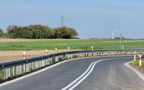 Oznaczenia na słupkach drogowych wzdłuż zakrętu drogi, prowadzącej przez pola i w pobliżu linii energetycznych.