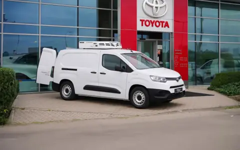 Biały, mały dostawczak z chłodnią na dachu stoi przed salonem Toyoty.