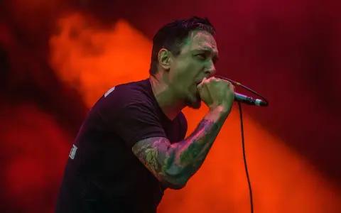 Chanteur au micro, le regard intense, comme s'il en avait marre de tout. Lumières rouges et orangées.