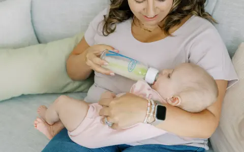 Kiedy zmienic przeplyw smoczka? Mama karmi dziecko butelką, obserwując, czy maluch nie ma problemów z jedzeniem.