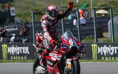 Piloto de MotoGP celebra victoria en su moto Ducati roja. Aunque no se especifica cuanto mide Marc Márquez, su presencia en la pista es imponente.