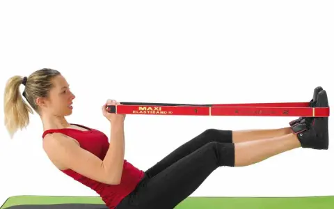 Femme faisant un exercice avec un élastique, jambes tendues et mains tenant la bande rouge.
