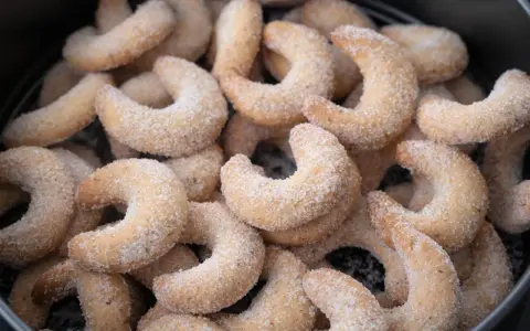 Ein Haufen frisch gebackener Vanillekipferl, bedeckt mit feinem Zucker, wartet darauf, genossen zu werden.