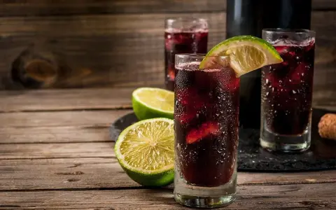 Orzeźwiający hiszpański napój alkoholowy z lodem i limonką, podany w szklankach na drewnianym stole.