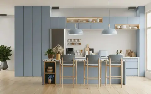 Cuisine moderne aux meubles bleus doux, avec un îlot central et des tabourets. L'éclairage doux crée une ambiance couleur blanc chaud.