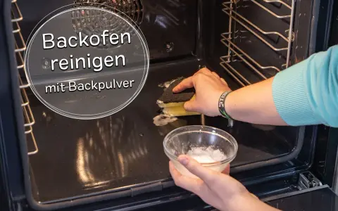 Backofen reinigen mit Backpulver: Eine Hand schrubbt mit einem Schwamm, die andere hält eine Schüssel mit der Reinigungspaste.