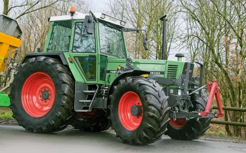 Zielony traktor Fendt 615 LSA z czerwonymi felgami, gotowy do pracy. Poznaj jego dane techniczne!