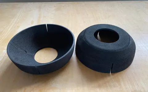 Zwei schwarze EPP-Platten, geformt wie Trichter und Zylinder, liegen auf einer Holzoberfläche.