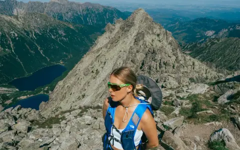 Kobieta w okularach i niebieskim plecaku na tle górskich krajobrazów. Beskid Śląski oferuje takie widoki i atrakcje.
