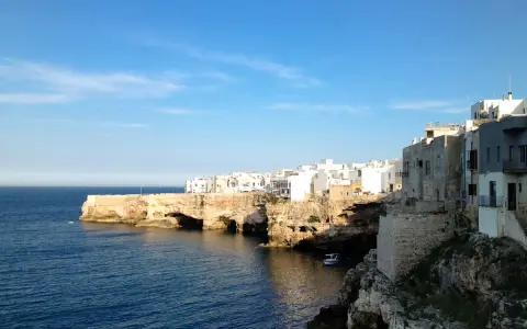 Scogliere bianche e case a picco sul mare blu, un'ottima idea per cosa visitare vicino Alberobello.