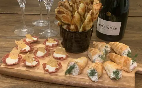 En flaska Bollinger och en bricka med läckra tilltugg till bubbel: små salta korgar, smördegsrullar och ostpinnar.