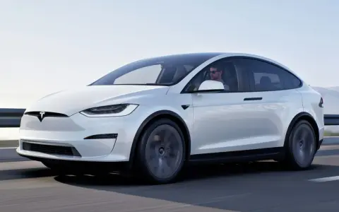 Biała Tesla Model X w ruchu. Zastanawiasz się, ile kosztuje Tesla? Ten luksusowy SUV elektryczny to marzenie wielu kierowców.