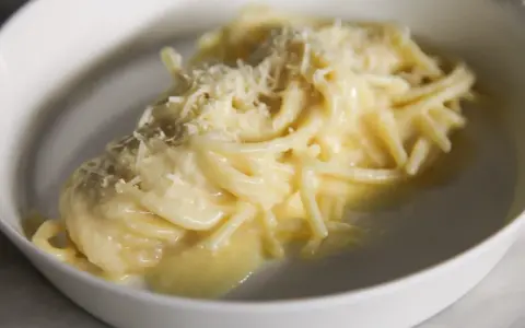 Un piatto di pasta burro e parmigiano, cremoso e invitante, con una spolverata di formaggio grattugiato.