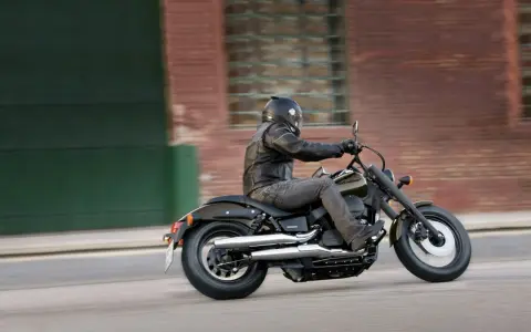Motocyklista na Honda Shadow 750, z uwzględnieniem danych technicznych, pędzi ulicą.