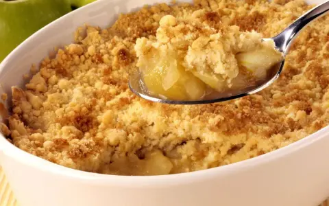 Une cuillère de crumble aux pommes, parfait pour suivre la recette Cyril Lignac. Des pommes fondantes sous une pâte croustillante.