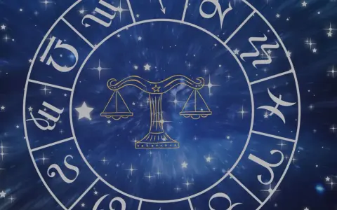 Złoty symbol wagi, jeden z dwunastu znaków zodiaku, na tle gwieździstego, niebieskiego kosmosu.
