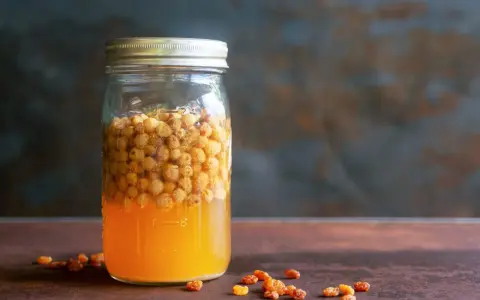 Glas mit süßem Saft und Rosinen, bereit, um Hefe selber machen zu beginnen.