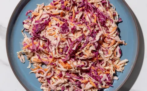 Insalata colorata con cavolo cappuccio rosso, carote e semi di senape, condita con una salsa cremosa.
