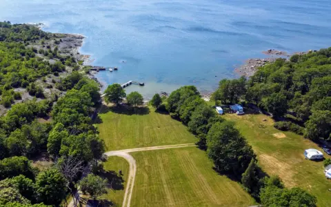 Vacker vy över camping i Blekinge med husvagnar vid en brygga och grönskande skog.