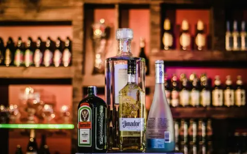 Butelki alkoholi na półce barowej: Jägermeister, tequila El Jimador, Absolut i Hypnotiq. Czy wiesz, whisky ile procent ma?