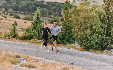 Coppia corre su strada sterrata, immersa nel verde. Il loro passo è un fondo lento, godendosi la natura.