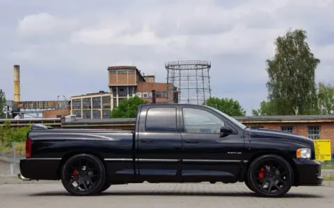Czarny Dodge Ram 1500 SRT-10, potężny pickup, prezentuje swoje imponujące ramiona na tle postindustrialnego krajobrazu.