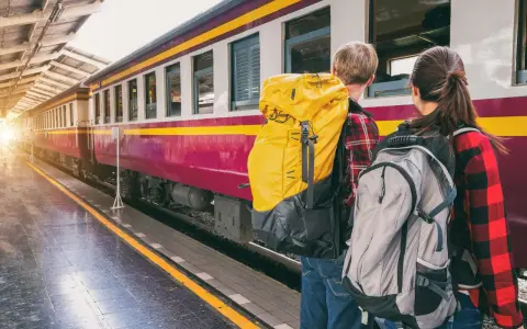 Zwei Rucksacktouristen warten am Bahnsteig auf ihren Zug. Mit ihrem world pass sind sie bereit für neue Abenteuer.