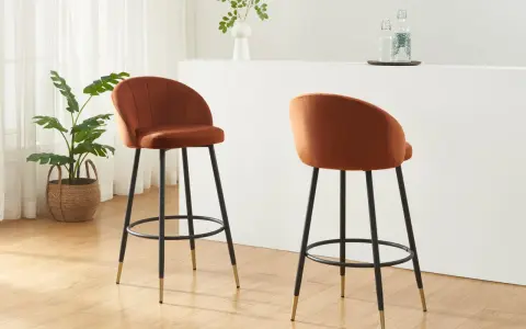 Due poltrone sgabello color ruggine, con gambe nere e dettagli dorati, in un ambiente moderno con piante e una barra.