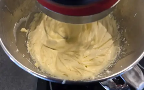 Un robot pâtissier mélange une crème onctueuse, prête à devenir une délicieuse crème mousseline café.