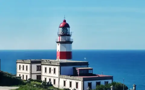 Faro blanco y rojo en la costa, un punto de referencia en la ruta de Vigo a Baiona.