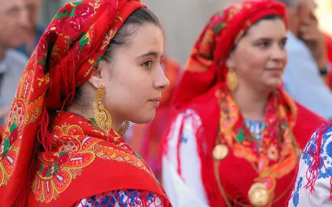 Giovani donne con foulard rossi ricamati e grandi orecchini dorati, un'immagine che evoca la tradizione di fare il portoghese con eleganza.