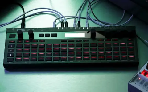 Zielony Korg SQ-64 z podświetlanymi na czerwono przyciskami, otoczony innymi syntezatorami i klawiaturą, tworzy scenę do tworzenia muzyki.