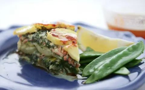Laxpudding med gravad lax, potatis och dill. Serveras med sockerärtor och citronklyfta.