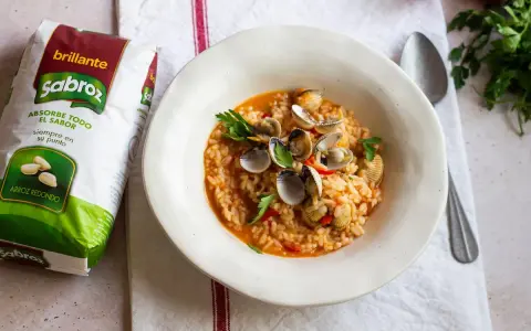 Delicioso arroz con berberechos, preparado con arroz redondo Sabroz, adornado con perejil fresco.