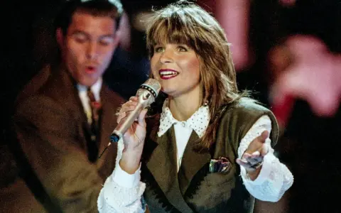Carola sjunger, en av de svenska bidrag som vunnit Eurovision. Hon håller en mikrofon och gestikulerar.