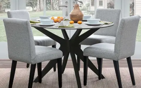 Ideas para decorar una mesa redonda: centro de mesa con jarrón y naranjas, platos y servilletas.
