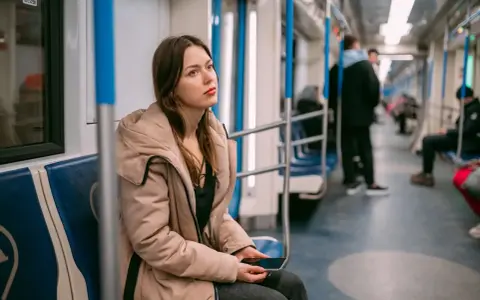 Młoda kobieta w beżowej kurtce siedzi w metrze, zamyślona. Może właśnie wraca z wizyty u lekarza, który wystawił jej L4 z powodu wypalenia zawodowego.
