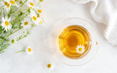 Un mazzolino di margherite e una tazza di tisana dorata. Nonostante la sua apparenza innocua, la camomilla fa male al cuore se consumata in eccesso.