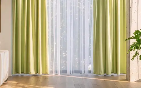 Helle, grüne Gardinen und zarter weiße Stores schmücken das Fenster. Diese Gardinen dekorieren den Raum und lassen viel Licht herein.