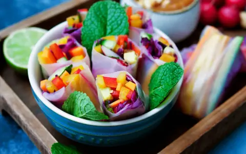 Frische Sommerrollen mit buntem Gemüse, Minze und einer Limettenspalte. Ein leichtes Sommerrollen Rezept für heiße Tage.
